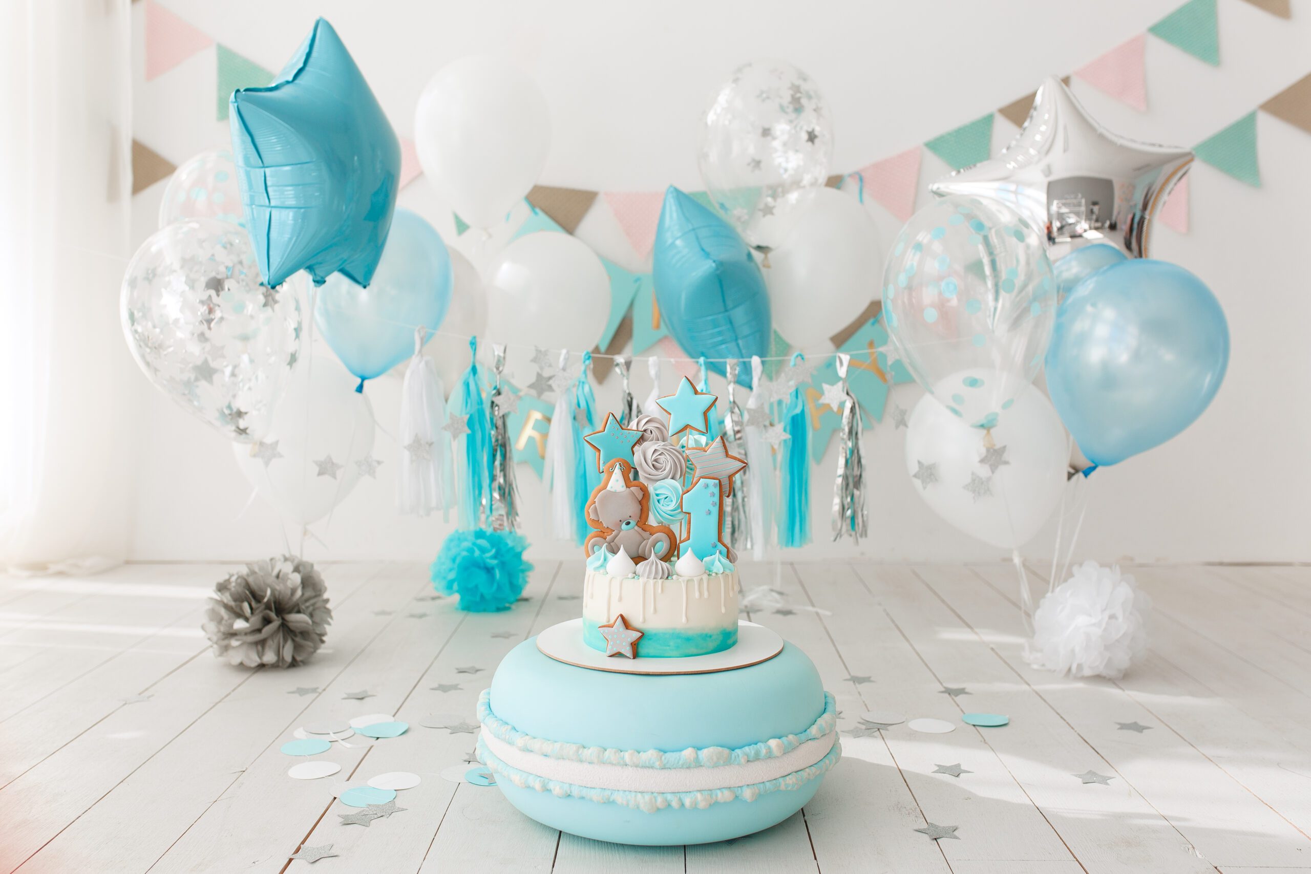 First birthday decorated room with blue cake standing on big macaroon.