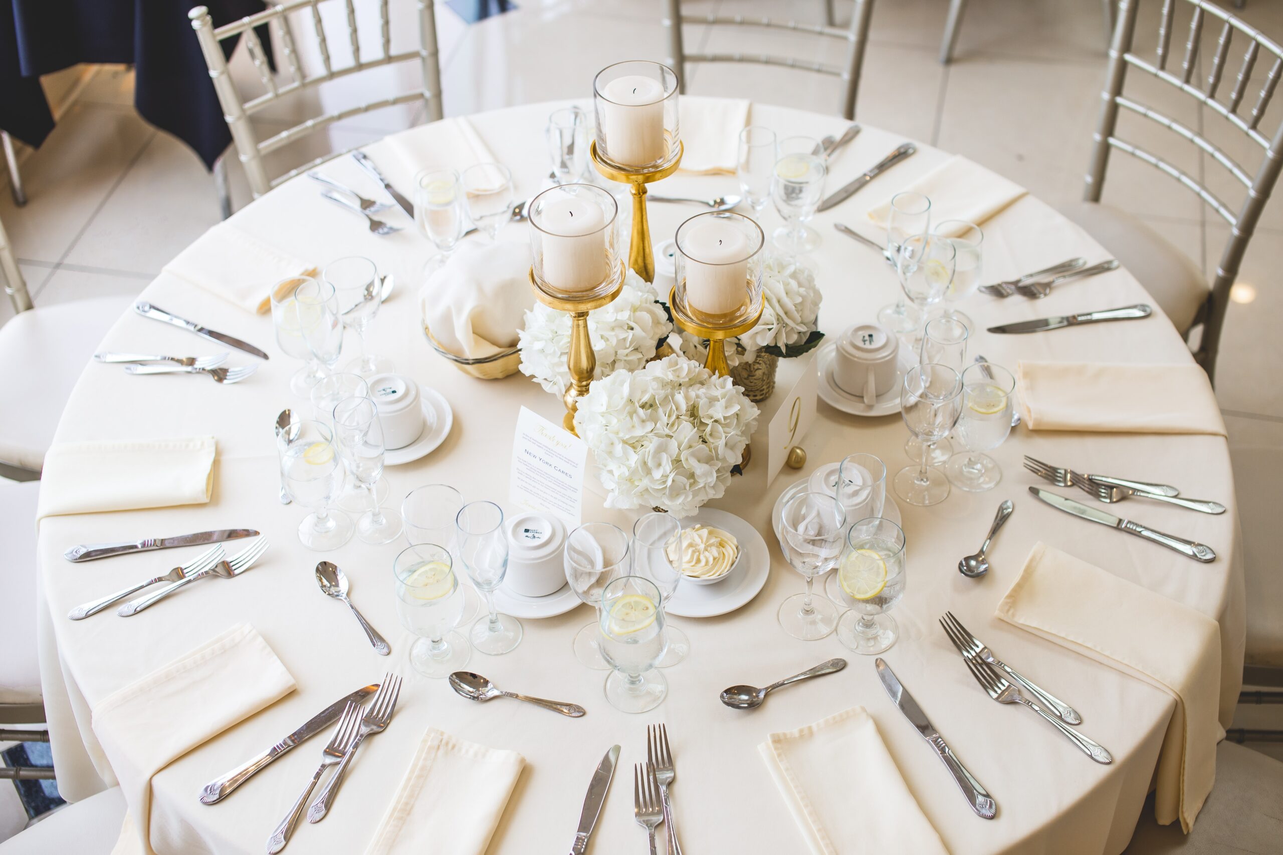 A shot of white flower bouquets and pillar candles in gold candelabra on a wedding table